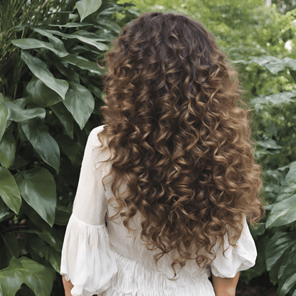 Long, hydrated, curly hair showcased against lush greenery, emphasizing frizz-free, defined curls.